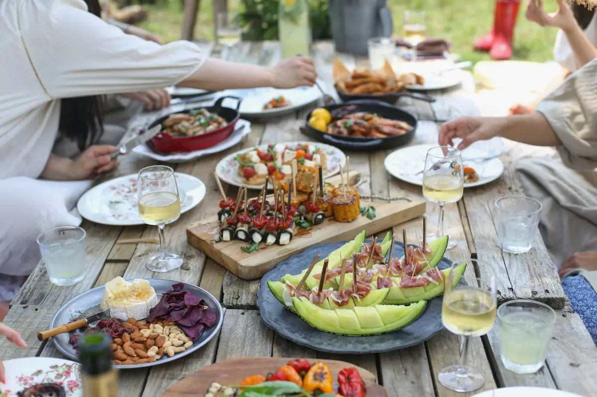 An outdoor table full of sharing plates, drinks and salads