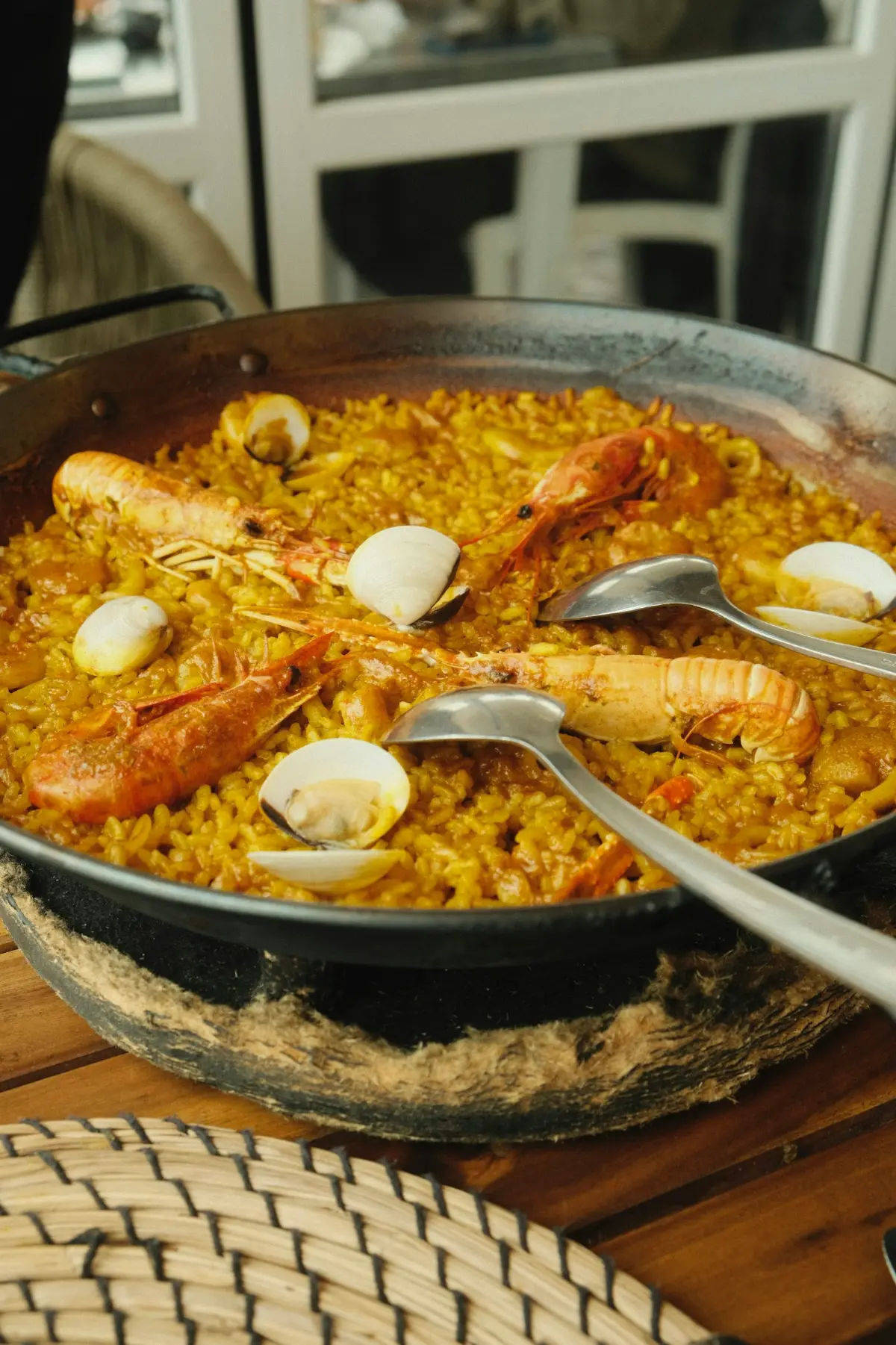A pan of seafood paella on a table with serving spoons
