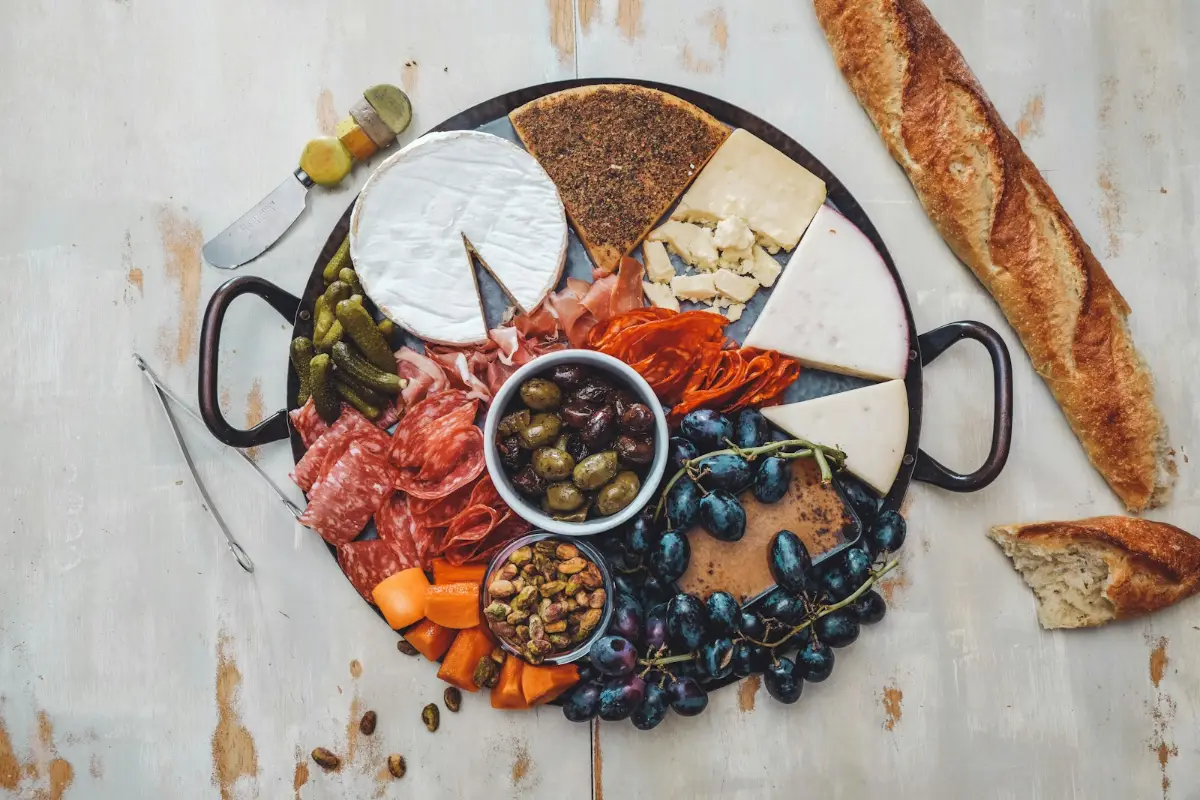 A board of cheeses, cured meats, olives and grapes with bread